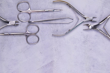 A set of cosmetic tools for manicure and pedicure stand on a concrete background. tweezers,...