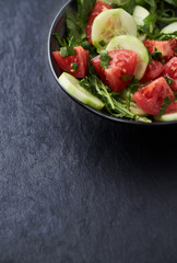Salad with Tomatoes, Cucumber and Rocket on stone Background. Healthy Snack Idea. Copy space. 