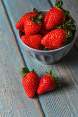 Blue beautiful organic strawberries in a blue bowl on a blue wooden background.