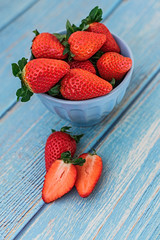 Blue beautiful organic strawberries in a blue bowl on a blue wooden background.