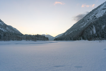 beautiful sunset in the mountains Alps in winter - with a blue yellow heaven - sunset between the mountains Germany L&ouml;densee -  reflection in snow - winter landscape