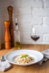 Spaghetti carbonara with pancetta, eggs and cheese in white bowl on the wooden table