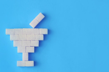 sugar cubes on a blue background, a glass of sugar, a concept of a sweet drink showing that there is a lot of sugar inside the drink, place for text, a drinking tube inside the glass