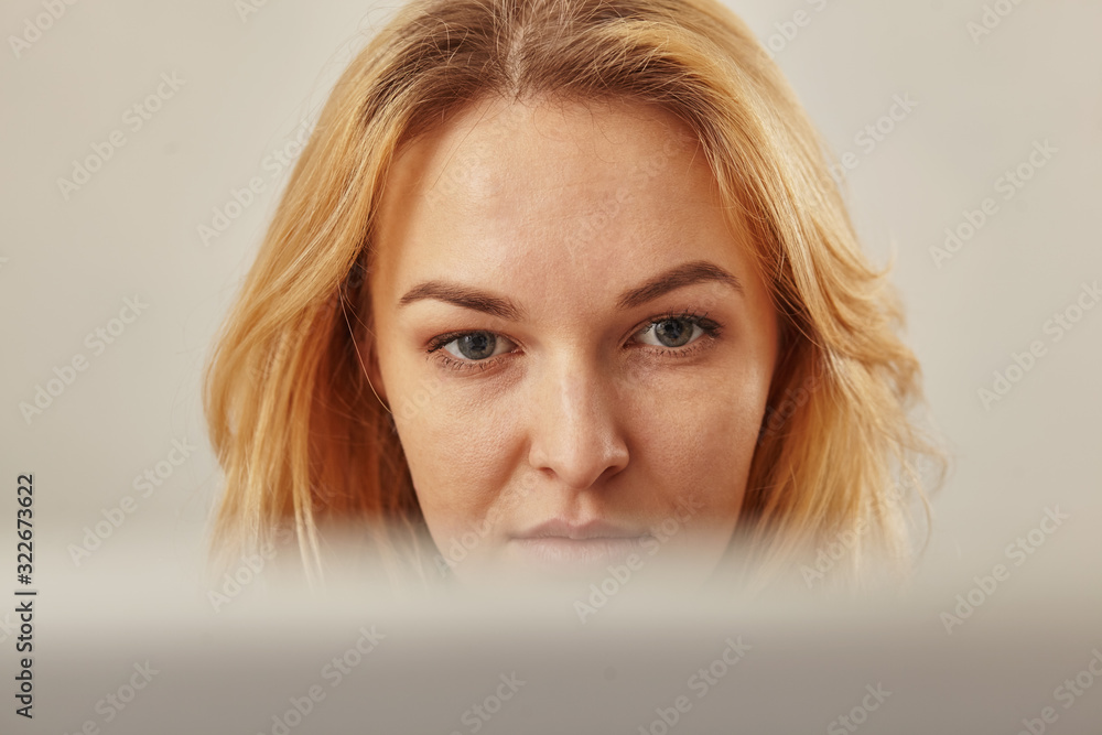 Wall mural closeup of a woman who looks closely at her computer screen