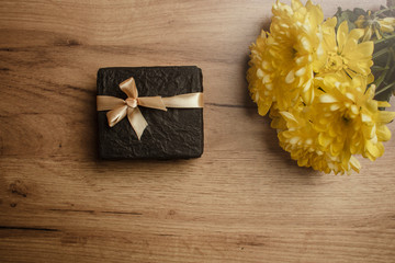 Gift box on the wood background with a  yellow flowers. Holiday surprise. Lifestyle. Holiday card.