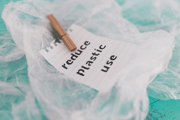 Reduce plastic use message with wooden peg on top of plastic bags, sustainable living