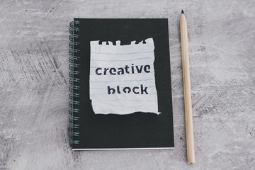 scrunched paper with Creative Block text on desk with notepad, lack of inspiration