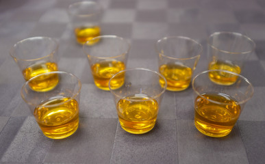 small tasting cups with golden liquid on grey background table