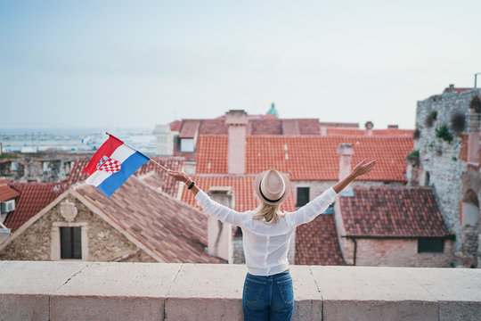 Enjoying vacation in Split. Young traveling woman with national croatian flag enjoying old town view.