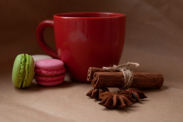 Red cup with macaroon and spices on craft paper background
