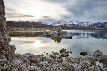 View of a Saline Soda Lake with Snow Capped Eastern Sierra Navada Mountains on a Cloudy Day in the Afternoon with Sunlight Shinning Through the Cloud 
