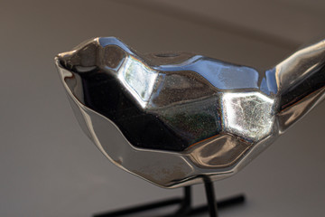 Steel bird. Beautiful sculpture. Minimalism in design. Natural light. Silver figure.