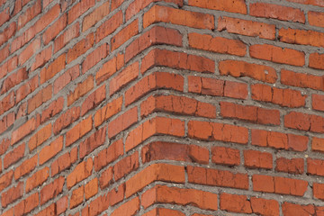 Brick wall texture. View of the brickwork from the corner of the building. Red background. Cement bonded building material. Part of the design.