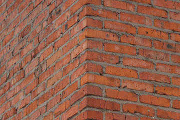 Brick wall texture. View of the brickwork from the corner of the building. Red background. Cement bonded building material. Part of the design.