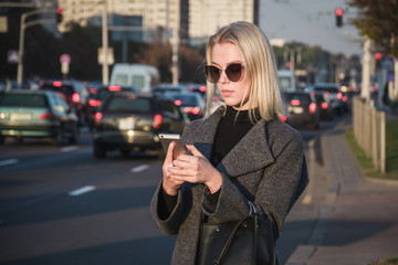 urban scene, a blonde girl calls a taxi through a mobile application