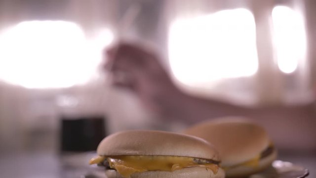 man sits in a cafe and drinks soda against the background of burgers