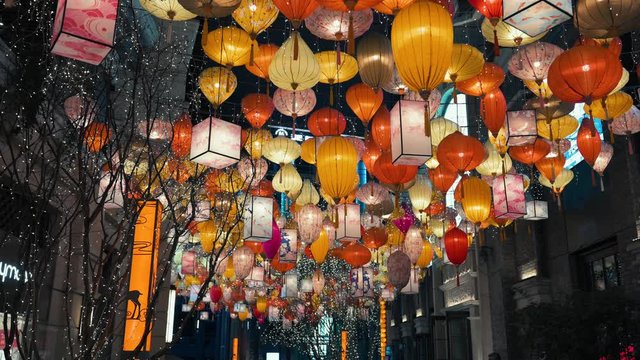 Lots of colorful different shapes oriental lanterns in famous touristic place hanging between the buildings. Preparation to celebrate the holiday and Lunar New year. Asian style traditional decoration