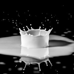 milk drips onto the black glass, forming a crown-shaped spray