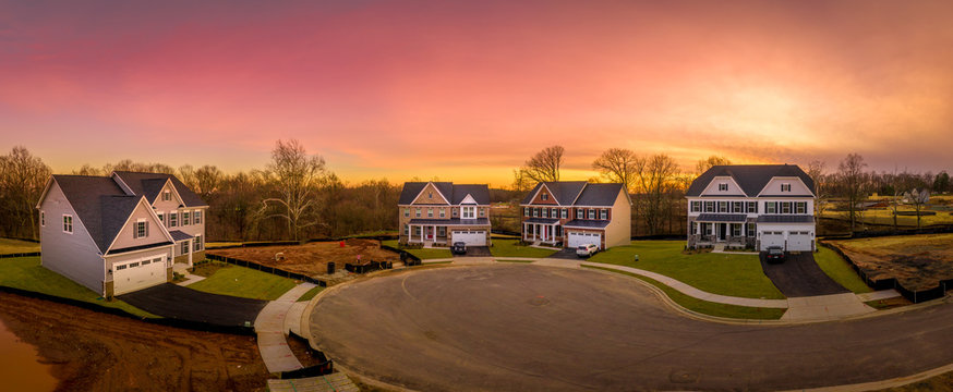 Aerial sunset view of a paved cul-de-sac at a USA new construction American real estate site with some colonial luxury houses built around it and some lots are empty
