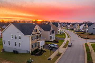 Aerial sunset view of curving contemporary American neighborhood street with newly constructed single family homes in the East Coast United States