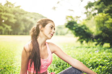 Naklejka na ściany i meble Portrait of young beautiful woman sitting after break workout at park,Happy and smiling,Relaxing time