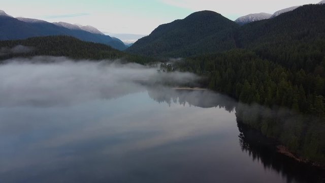 Morning on the mirror-like lake covered with the low fog