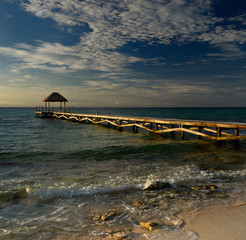 Thatched roof gazebo on the end of a dock on the Mayan Riviera at dawn