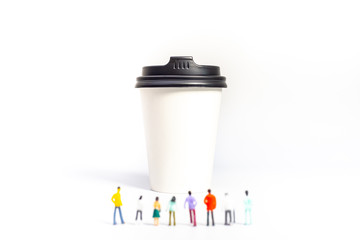 Miniature People and Coffee to-go Cup on white background. Cafe menu concept. Shallow depth of field.