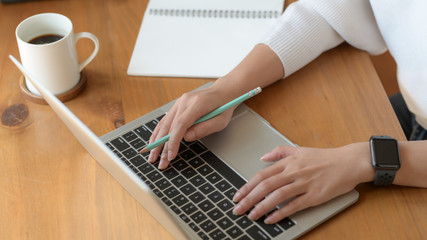 Close-up view of girl working on her project while typing on laptop computer