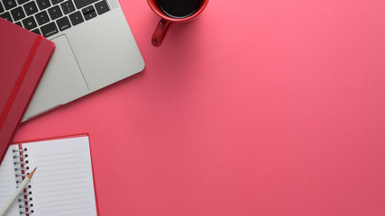 Overhead shot of workspace with laptop and copy space on pink table