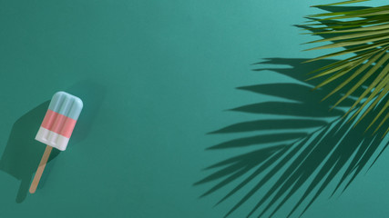 Top view of pastel popsicles, palm leaf on green background