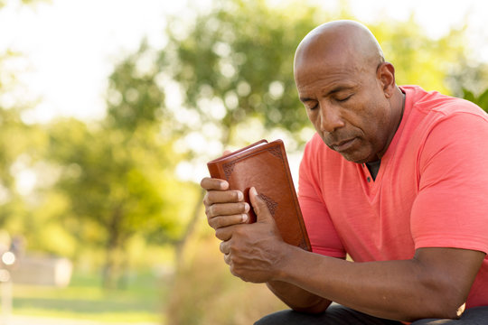 African American Man Praying And Reading The Bible.