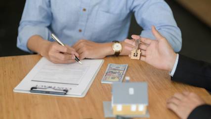 Cropped shot of real estate agent giving house key to customer