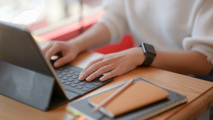 Fototapeta premium Cropped shot of female freelancer typing on digital tablet