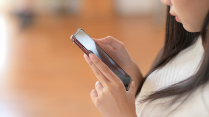 Close up view of a girl using smartphone with blurred living room background