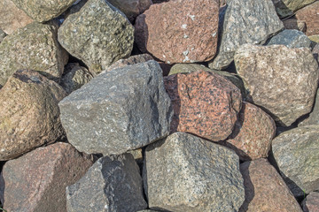 A pile of granite boulders piled on top of each other in gray, beige, and brown hues with rough edges. Natural organic mineral background with a play of light and shadow for the design.