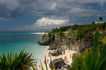 Sea cliff at Tulum Mexico with bathers on the beach and temple 54