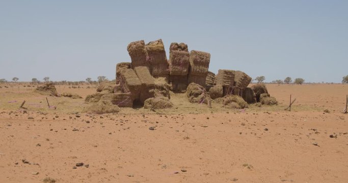 Large pile of hay bales stacked up in the middle of a paddock in Outback Australia