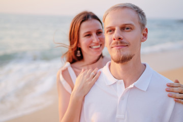 Obraz premium Love and romance. Honeymoon on the sea shore. Beautiful loving couple in white cloth embracing on the beach.