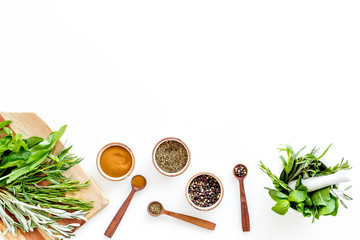 Making spices. Herbs in motar and dry flavorings on white table top-down copy space