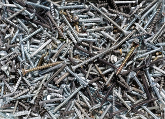 Close-up view of a heap of new and used screws for construction and carpentry