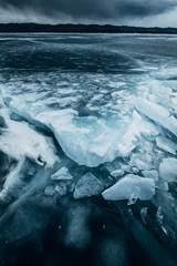Russia. Lake Baikal. March. Cracked ice. Blocks of ice. Dark cloudy stormy sky. Blue photo