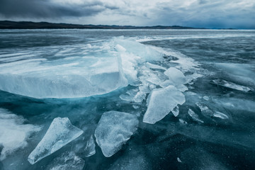 Russia. Lake Baikal. March. Cracked ice. Blocks of ice. Dark cloudy stormy sky. Blue photo