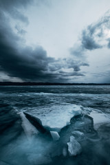 Russia. Lake Baikal. March. Cracked ice. Blocks of ice. Dark cloudy stormy sky. Blue photo
