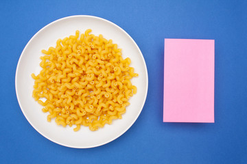 Italian pasta cavatappi in a white plate on a colored background with pink paper for text. Top view.