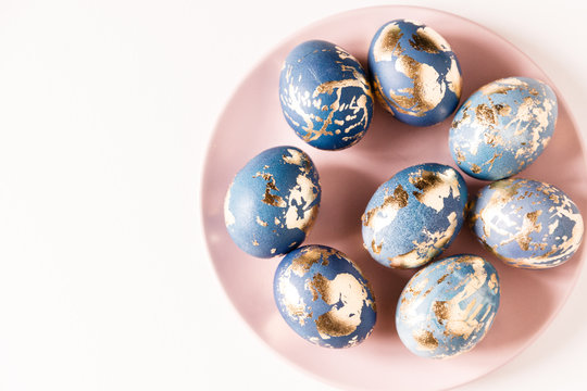 Blue easter eggs decorated gold patel on the pink plate. Free space for text