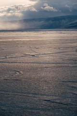Baikal, Russia, March. Yellow light from the sun covers the ice on the lake. Far away on a mountain background