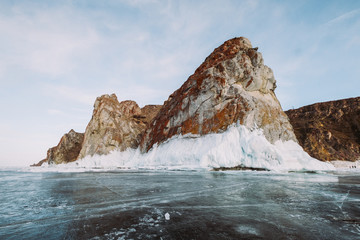 Fototapeta na wymiar Russia. Lake Baikal. March. Rock 3 brothers. Big beautiful rock in orange shades covered with ice. Around is also a lake covered with ice.