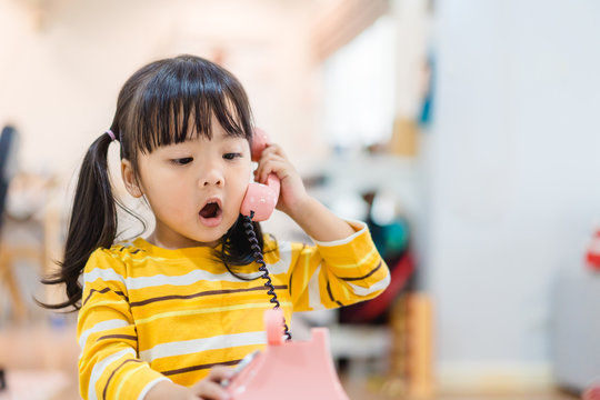3 years old little asian girl holding vintage telephone talking and listening to her dad or father. Asian child girl call delivery food service in the morning.Children and vintage technology concept.