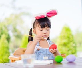 Cute little asian toddler girl wearing bunny ears on Easter day.Little asian Girl painting easter...